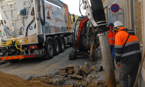 Photo du chauffeur de l'excavatrice en train de guider la buse du camion pour creuser sur travaux publics