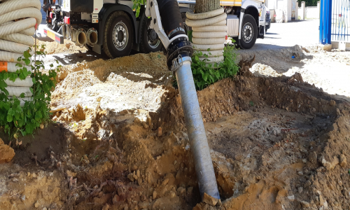 Photo de la buse de l'excavatrice qui creuse et aspire sur sol en terre pour un chantier de précision